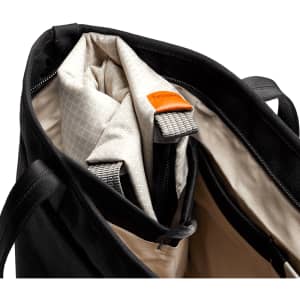 A black cooler bag with a cream interior, featuring a zippered opening and a logo tag.