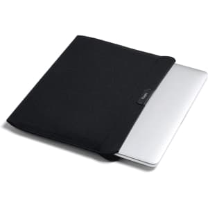A black laptop sleeve partially covering a silver laptop, featuring a small logo on the front.