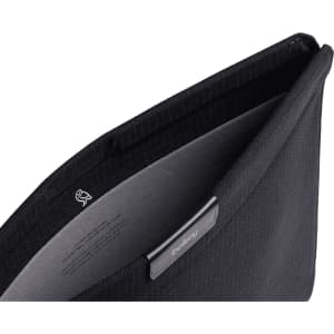 A black laptop sleeve with a soft interior lining and a logo. The opening reveals a sleek design.