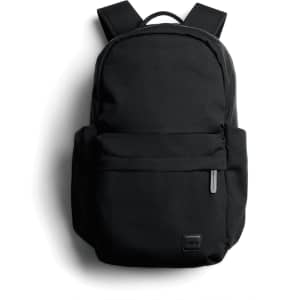 A black daypack with adjustable straps and a front pocket, featuring a branding logo.