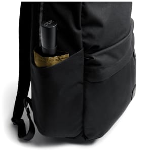A black daypack with a drink bottle in the side pocket, featuring a simple and sleek design.