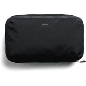 A black packing cube with a zipper and a small logo, designed for travel organisation.