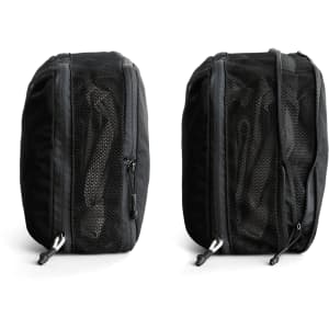 A black packing cube with mesh panels, featuring zip closures on both sides. It has a logo on one side.