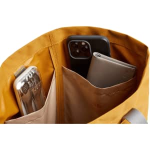 A yellow tote bag interior with two pockets holding a drink bottle and two smartphones.
