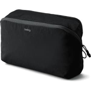 A black packing cube with a zippered mesh top, featuring branding on the front.