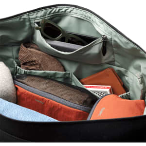A black duffel bag interior featuring various items, including a pair of sunglasses, a notebook, and orange pouches.
