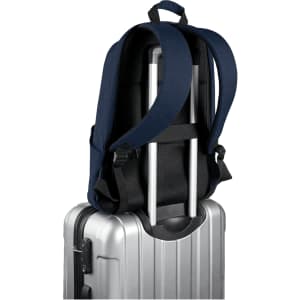 A navy blue laptop backpack with adjustable straps resting on a silver suitcase. It has a logo on the side.