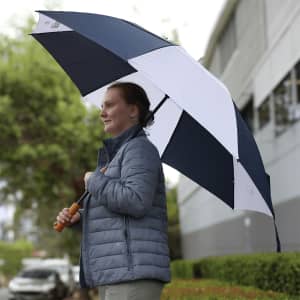 A golf umbrella featuring a navy and white design, held by a person wearing a grey jacket outdoors.