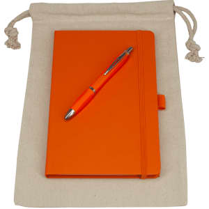 A drawstring bag in natural colour containing an orange journal book and an orange pen. The bag features a logo.