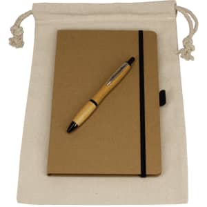 A drawstring bag in cream contains a brown journal book and a wooden pen. The set is neatly arranged for display.