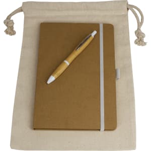 A natural-coloured drawstring bag containing a brown journal book and a wooden pen. The bag has a branding logo.