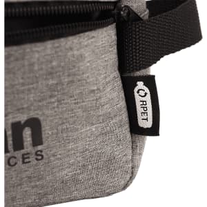 A grey bag with a zipper and a strap, featuring a small tag. The bag has a simple, modern design.