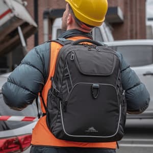 A sturdy, black High Sierra Access 4.0 backpack, worn by a worker in an orange vest and hard hat.