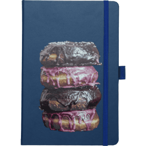 A navy notebook featuring a stack of chocolate and pink iced doughnuts on the cover. The notebook has a logo and an elastic band.
