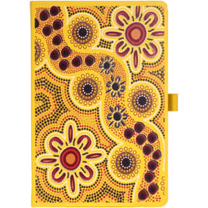 A yellow patterned journal with Aboriginal-inspired designs, featuring vibrant flowers and circular motifs, with a logo.