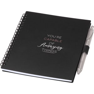 A black spiral-bound journal with a silver pen attached. The journal features motivational text and has a logo.