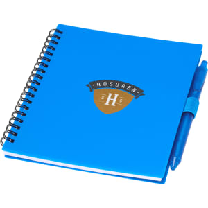 A blue journal with a spiral binding and a matching blue pen attached, featuring a logo.