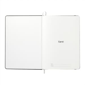 An open A5 hardcover notebook with a plain white interior and a logo on the first page. Features a black cover.