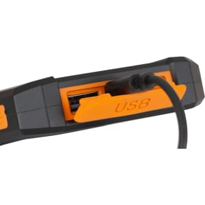 A solar power bank in black and orange with a USB port and cable connected. It has a rugged design.