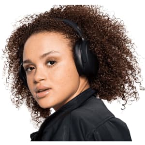 A pair of black Skullcandy Hesh ANC wireless headphones worn by a person with curly hair.