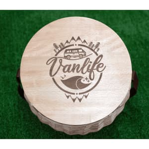 A circular wooden cooler basket lid featuring a "Vanlife" design with a camper van and wave illustration.