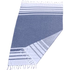 A Turkish beach towel featuring a navy blue and white design with striped patterns and fringed edges. It has branding.
