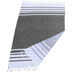 A grey and white striped Turkish beach towel featuring tasselled edges and soft fabric, ideal for beach use.