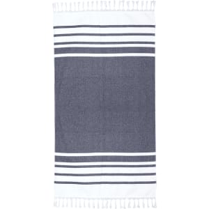 A Turkish beach towel in navy and white with decorative stripes and tassels along the edges.