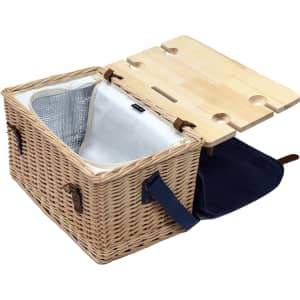 A wicker picnic basket in natural tones, featuring a wooden top with drink holders and a navy blue lining.