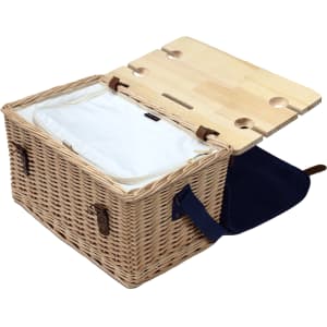 A wicker picnic basket in natural tones with a wooden lid and insulated interior, featuring a dark blue handle.