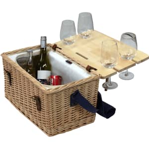 A wicker picnic basket with a wooden table attachment, two bottles, a can, and four glass tumblers.