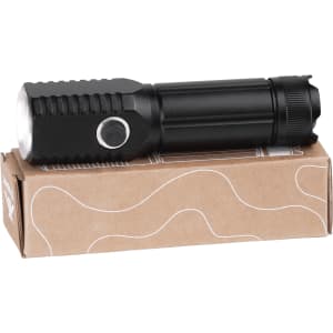 A black LED torch resting on a light brown cardboard box, featuring a textured grip and a push button.