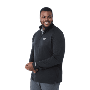 A man wearing a black quarter zip jacket with a logo, featuring a relaxed fit and standing pose.