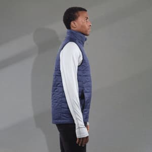 A navy puffer vest with a high collar, worn over a long-sleeve white top, featuring a logo on the chest.