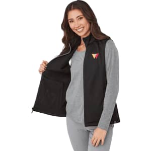 A woman wearing a black eco waterproof softshell vest, featuring a logo on the chest, with an open front.
