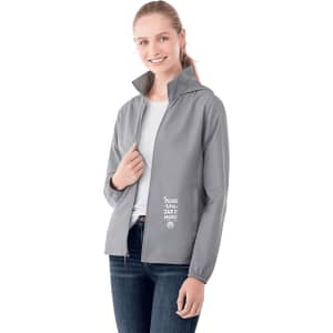 A woman wearing a grey packable rain jacket with a hood, featuring a logo and text on the front.