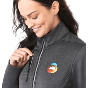A grey women's softshell jacket with a zippered pocket, featuring a colourful logo on the chest.