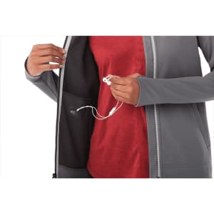 A grey women's full zip performance jacket with thumb holes, featuring an interior pocket for audio accessories.