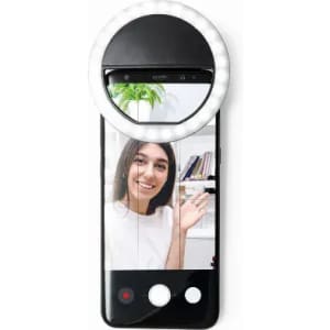 A smartphone with a circular selfie ring light attached, displaying a smiling person in a bright setting.