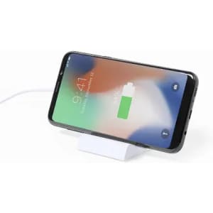A smartphone on a white charging stand, displaying a battery charging icon on its screen.