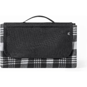 A picnic blanket in black and white plaid, folded with a black carry handle on top. Features a logo on the side.