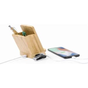 A wooden desk organiser with compartments for pens and a phone charging beside it.