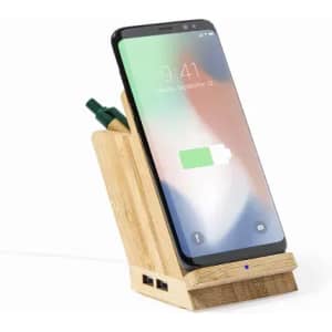 A wooden phone dock featuring a smartphone display, with a green pen and USB ports visible.