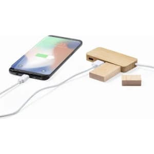 A wooden phone charger and a smartphone are connected via a charging cable. The charger features a minimalist design.
