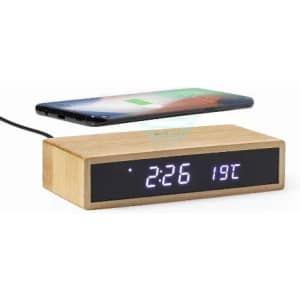 A wooden alarm clock with a digital display showing the time and temperature, with a smartphone placed above it.