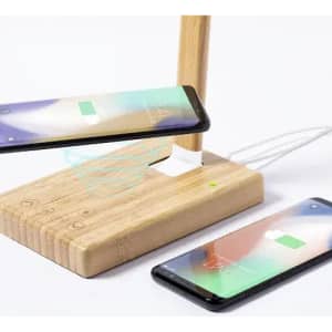 A wooden charging station with two smartphones, featuring wireless charging capability and multiple charging ports.