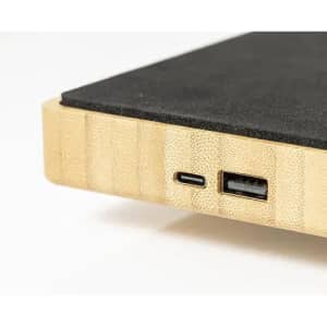 A wooden charging pad featuring a black surface, with USB-C and USB-A ports on the side.