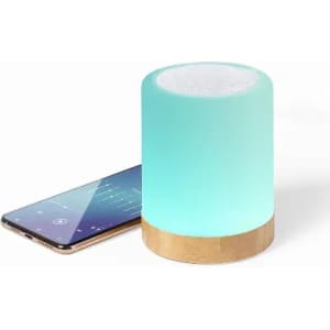 A speaker with a light feature, featuring a teal gradient and a wooden base, next to a smartphone displaying music.