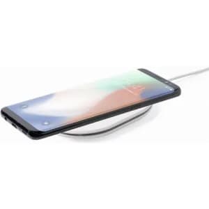 A smartphone charging on a sleek, circular wireless charger. The device is black with a vibrant screen display.