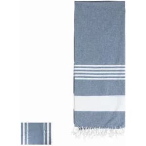 A blue and white patterned towel with fringe edges, featuring stripes and a smooth texture. It includes a logo.